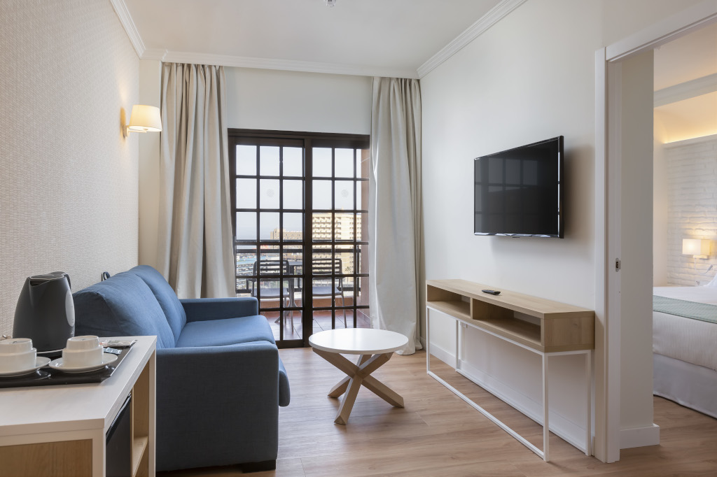 Salon moderne d'un appartement à Tenerife avec canapé, table et TV.