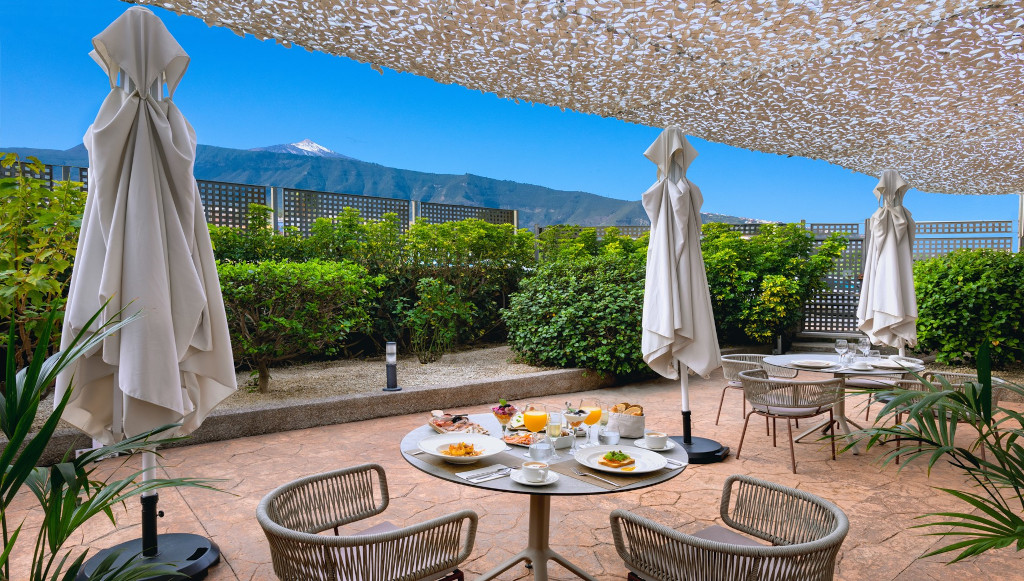 Salle à manger extérieure avec vue sur le Teide à Tenerife, tables dressées.