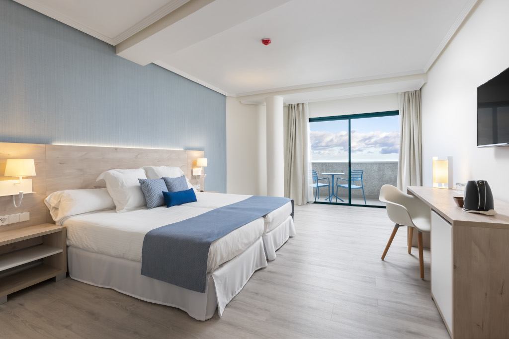 Chambre d'hôtel moderne à Tenerife avec balcon et vue sur mer.
