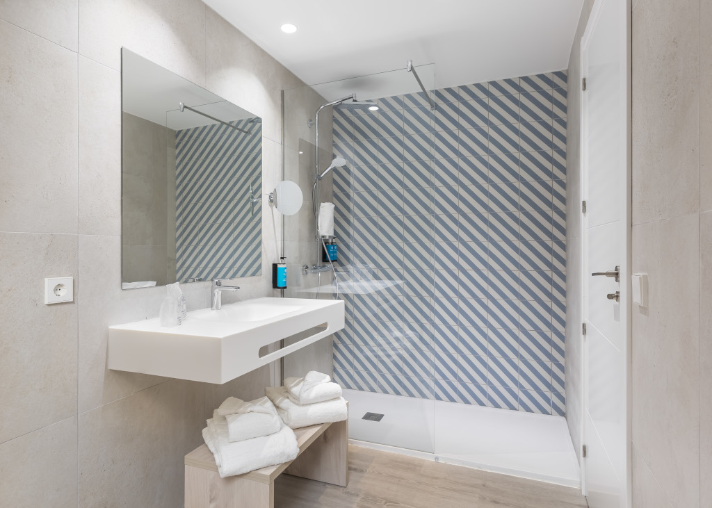 Salle de bain moderne à Tenerife avec douche et mur à rayures bleues.