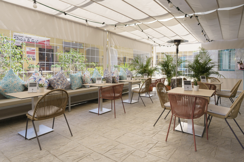 Terrasse de café à Tenerife avec tables, chaises et coussins colorés.