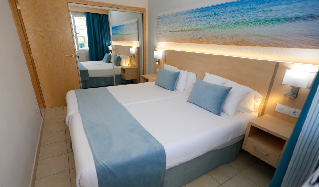 Chambre d'hôtel moderne à Tenerife avec lit double et décoration plage.
