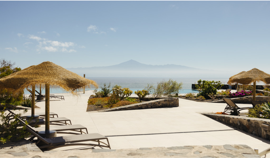 Chaises longues sous parasols avec vue sur l'océan et le Teide à Tenerife.