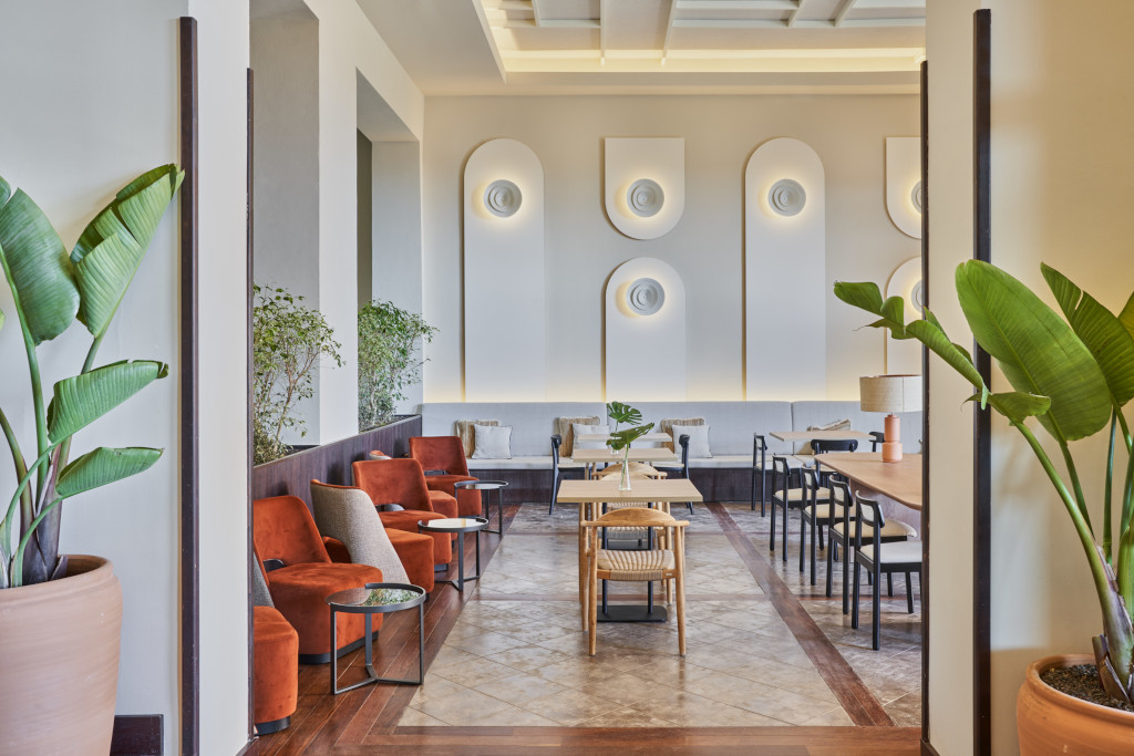 Chambre avec fauteuils et tables dans un hôtel à Tenerife, décorée de plantes et de panneaux muraux.