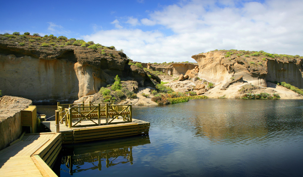Passerelle en bois au-dessus d’un lac avec des formations rocheuses à Tenerife.