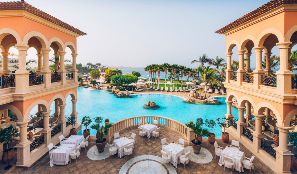 Vue sur une piscine et jardin de luxe à Tenerife avec palmiers.