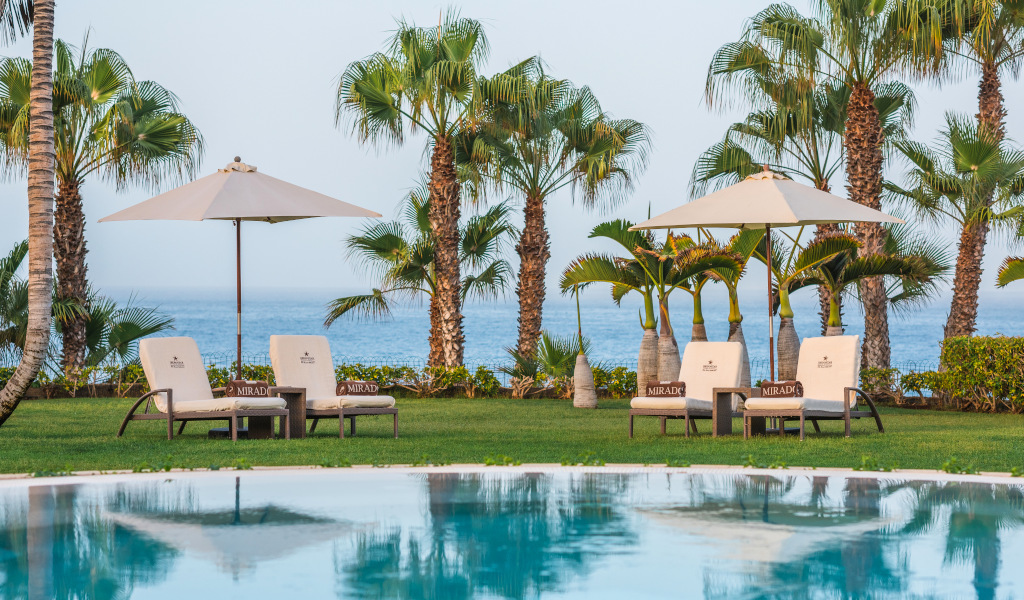 Chaises longues et parasols près d'une piscine avec vue sur la mer à Mirador Tenerife.