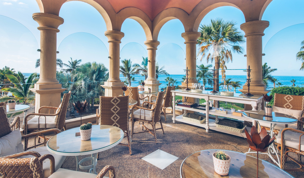 Terrasse avec vue sur l'océan à Tenerife, meublée de tables et chaises en osier.