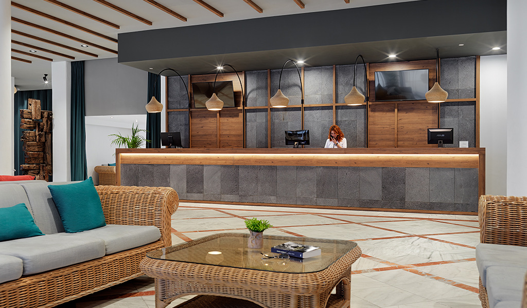 Réception moderne d'un hôtel à Tenerife avec canapés et comptoir en bois.