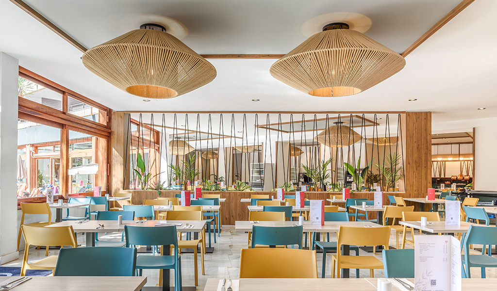 Salle de restaurant à Tenerife avec tables et chaises colorées.