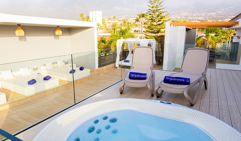 Jacuzzi et transats avec serviettes fergushotels.com sur une terrasse à Tenerife.