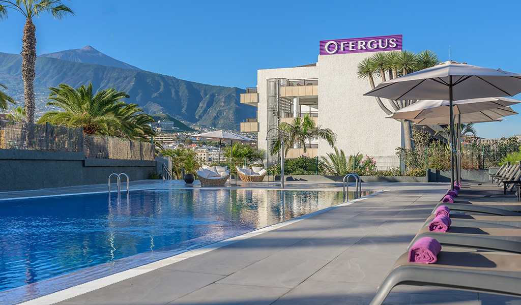 Piscine de l'hôtel à Tenerife avec vue sur la montagne et ciel bleu.