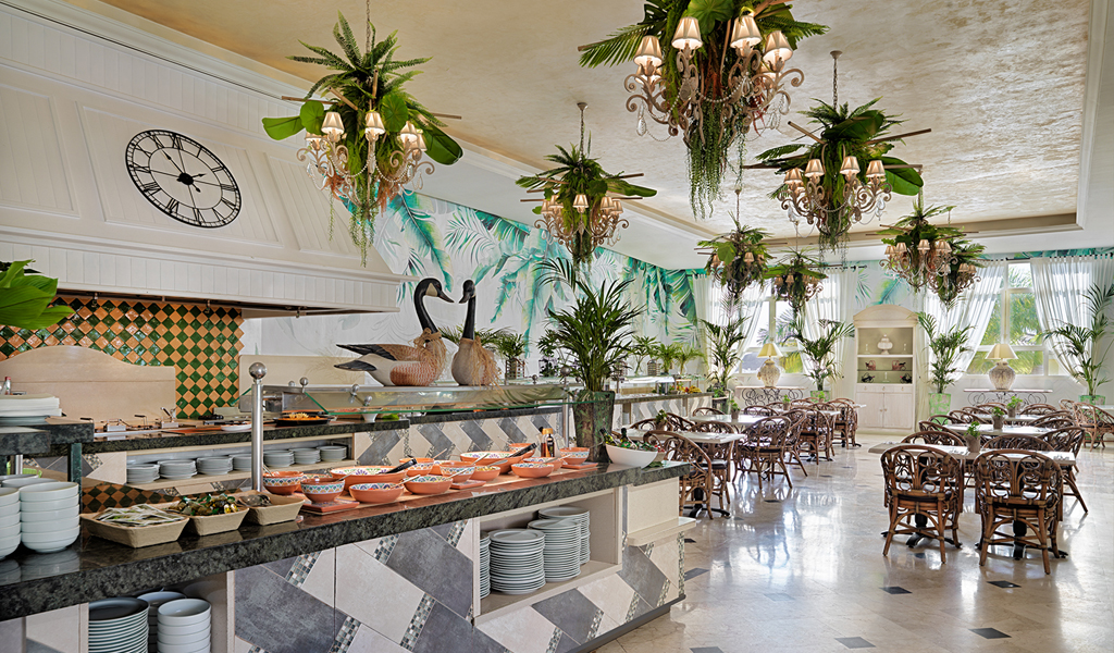 Salle de restaurant élégante à Tenerife avec tables, chaises foncées et plantes vertes.