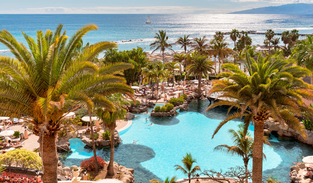 Piscine entourée de palmiers avec vue sur l'océan à Costa Adeje, Tenerife.