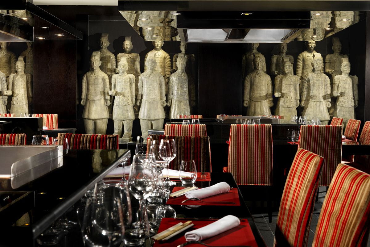 Restaurant à Ténérife avec des statues de guerriers et des tables dressées.