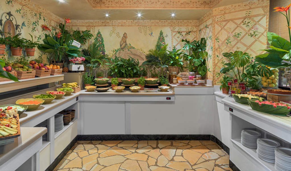 Buffet de fruits tropicaux et salades à Tenerife, entouré de plantes vertes.