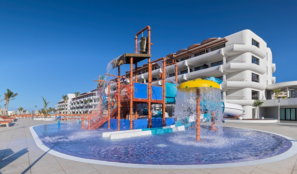 Aire de jeux aquatiques à l'hôtel en Tenerife, toboggans et parasol arrosant.
