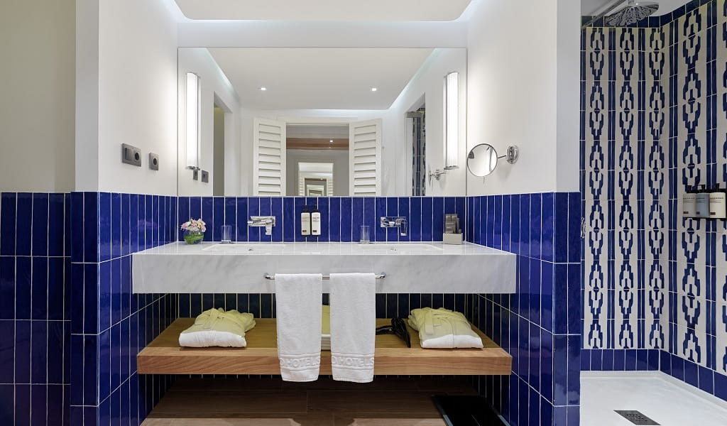 Salle de bains moderne avec carrelage bleu à Tenerife, serviettes et lavabos.