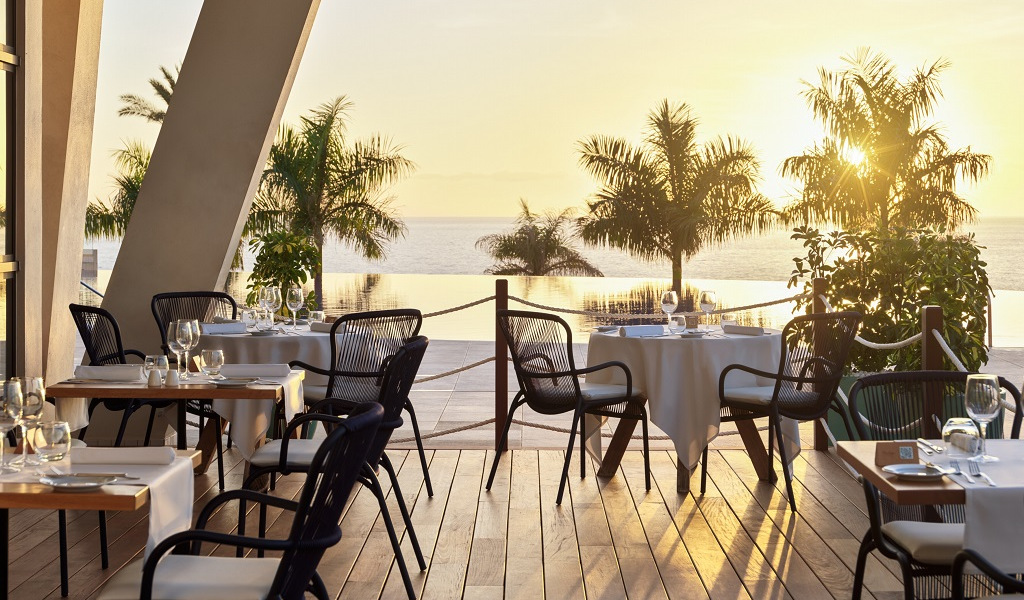 Tables de restaurant en terrasse avec vue sur la mer au coucher du soleil à Tenerife.