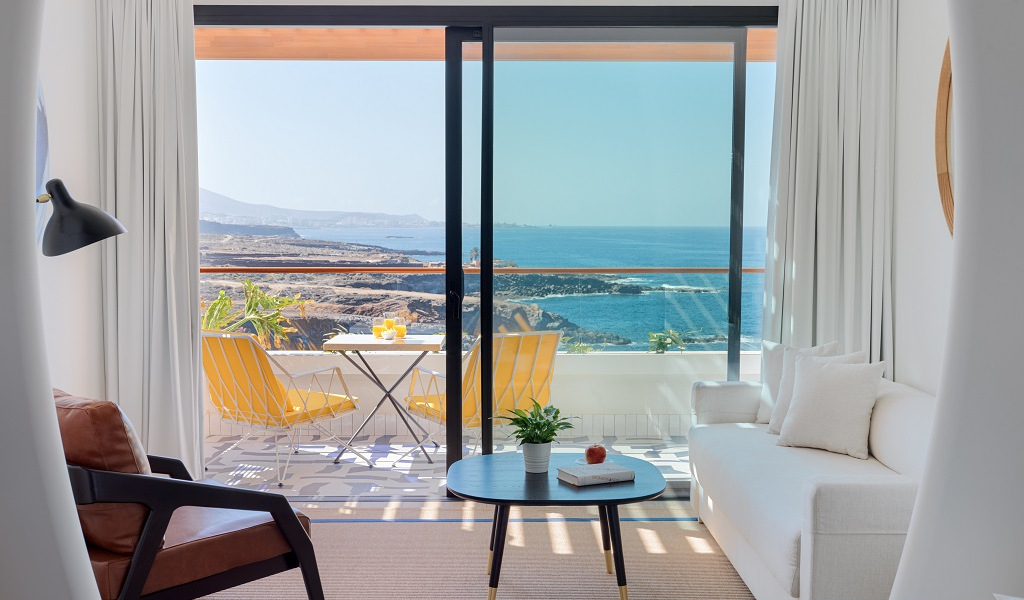 Salon avec vue sur la mer à Tenerife, terrasse avec chaises jaunes et table.