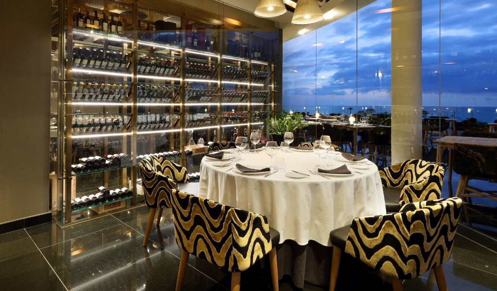 Table élégante dans un restaurant à Tenerife avec vue sur la mer et cave à vin.