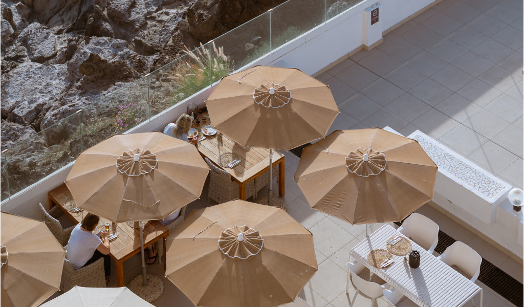 Tables en plein air sous parasols près de rochers à Tenerife.
