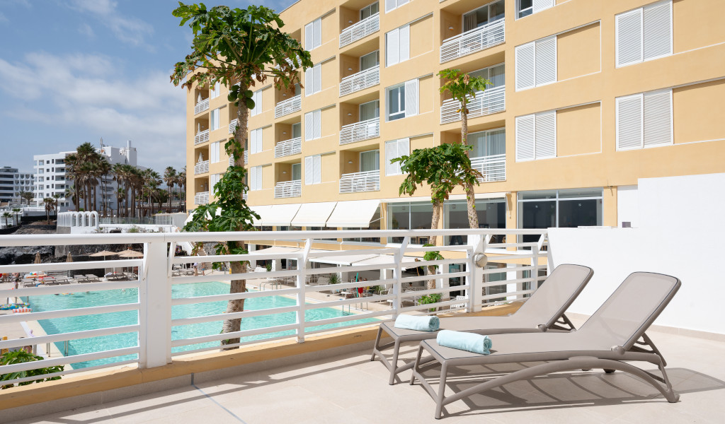 Chaises longues près d'une piscine d'hôtel à Tenerife avec des appartements en arrière-plan.