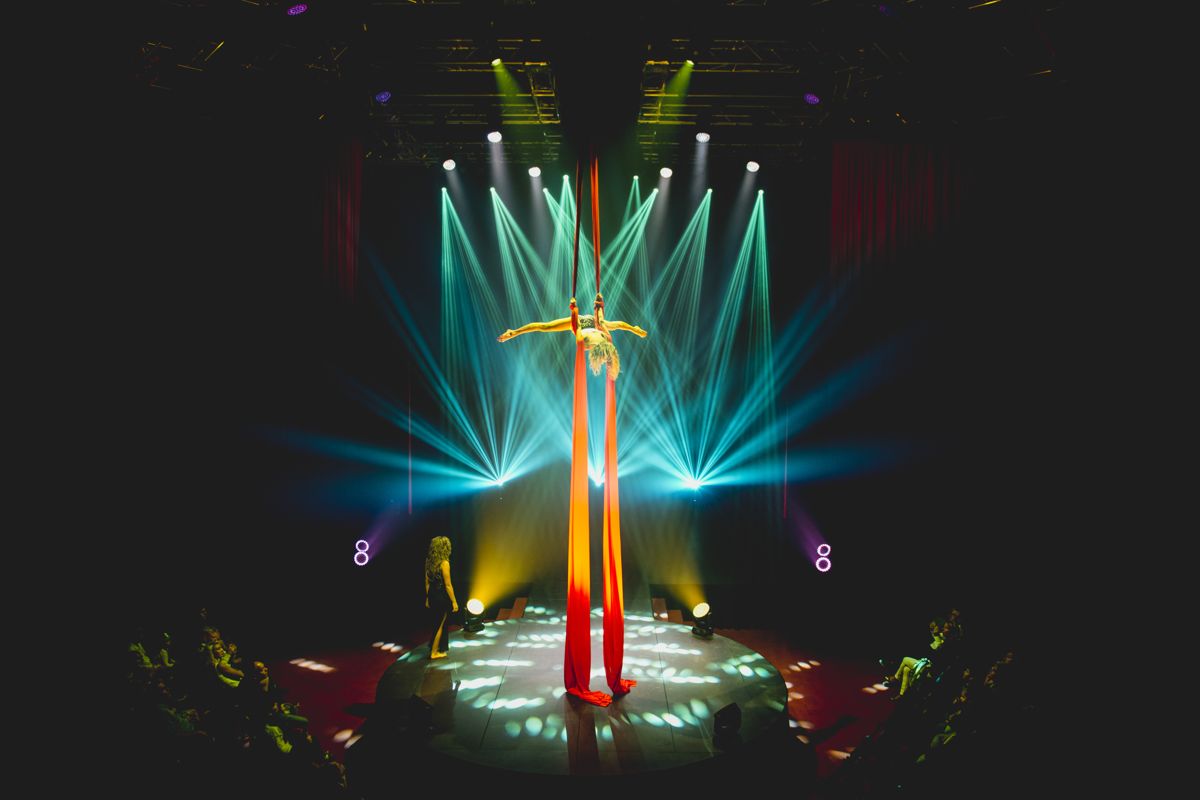 Artiste de cirque suspendu dans des draps rouges sous des lumières à Tenerife.