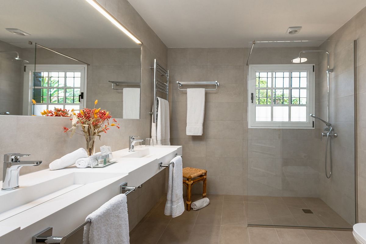 Salle de bain moderne avec douche, lavabo, miroir et fenêtre à Tenerife.
