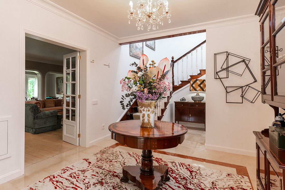 Hall d'entrée lumineux avec table en bois et fleurs, escalier en arrière-plan à Tenerife.