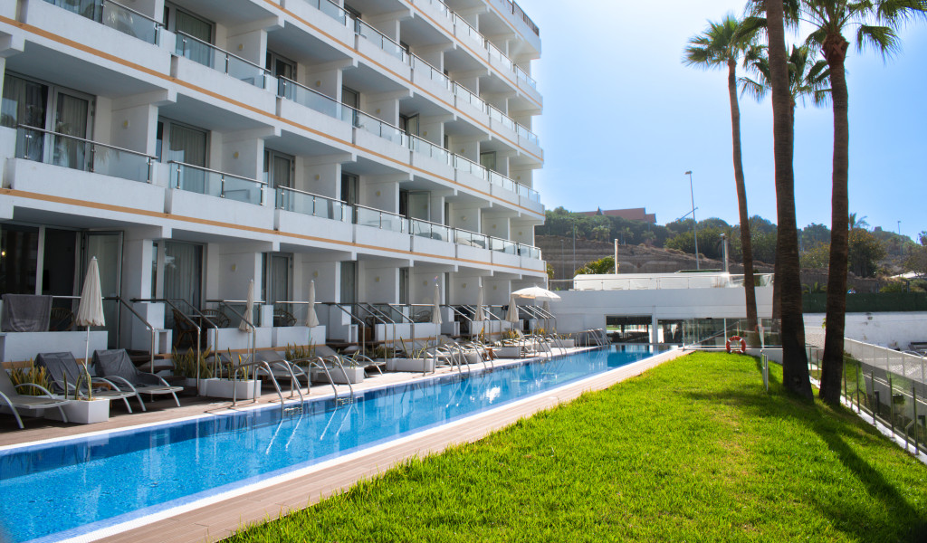 Bâtiment moderne à Tenerife avec piscine et palmiers devant.