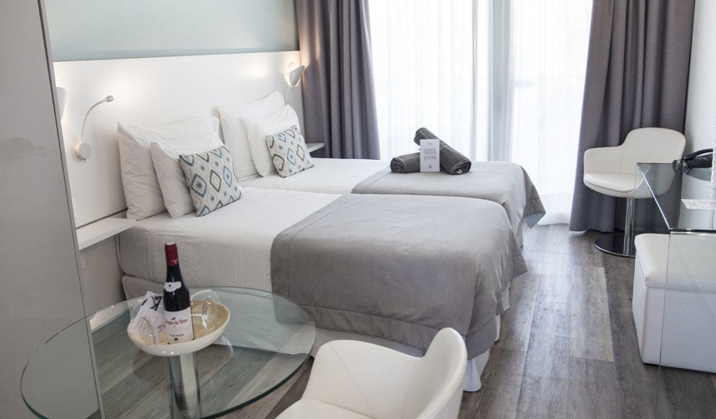Deux lits simples, table en verre et chaise dans une chambre moderne à Tenerife.