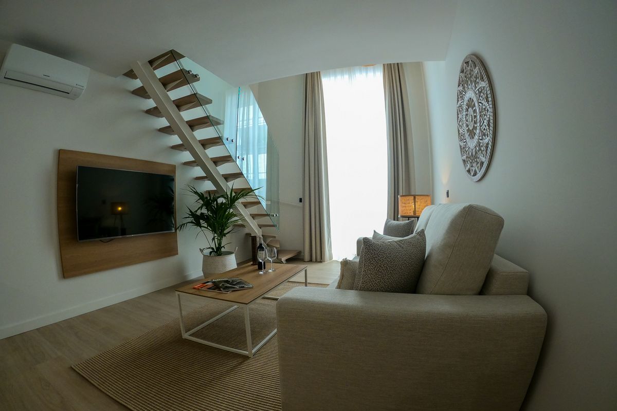 Salon moderne avec escalier en bois, canapé beige et télévision à Tenerife.