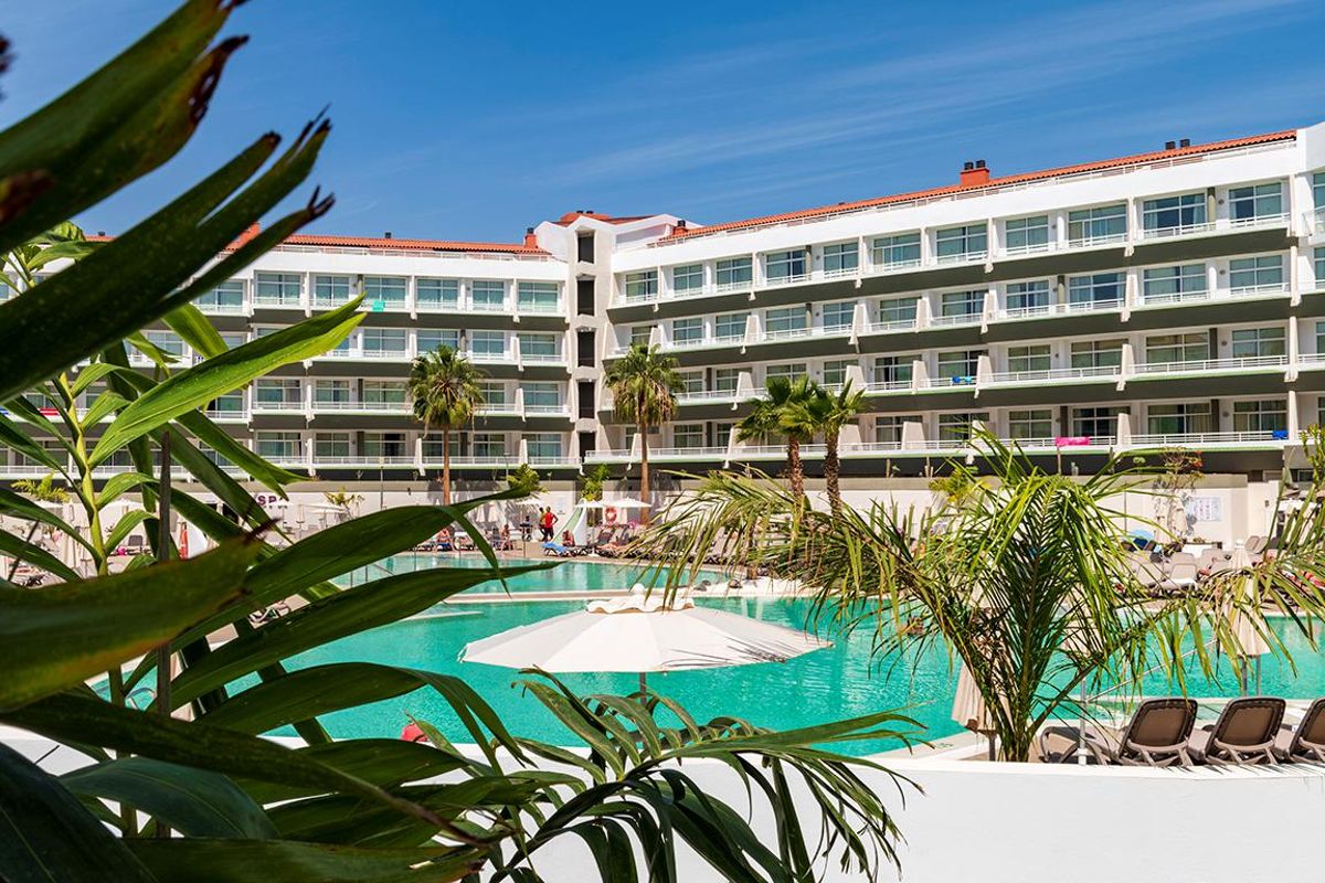 Hôtel à Tenerife avec piscine turquoise et palmiers au premier plan.
