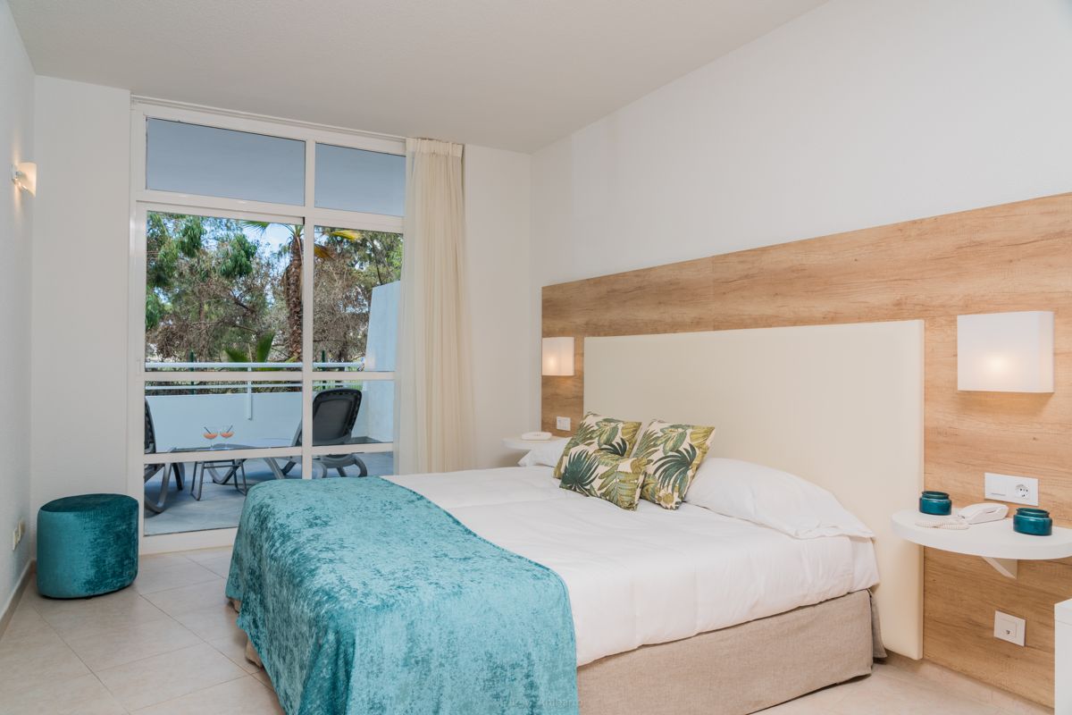 Chambre d'hôtel à Tenerife avec lit double et terrasse vue sur des arbres.