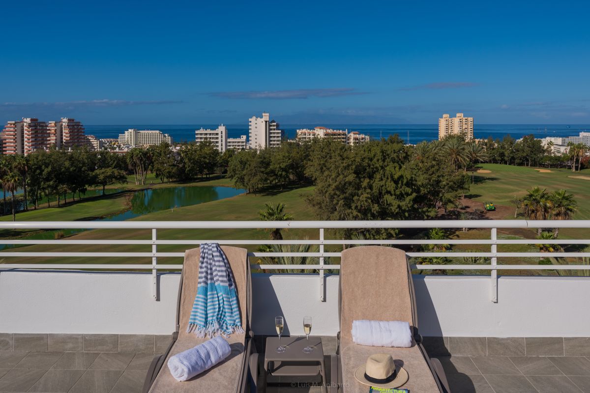 Deux chaises longues sur une terrasse surplombant un golf panoramique à Tenerife.