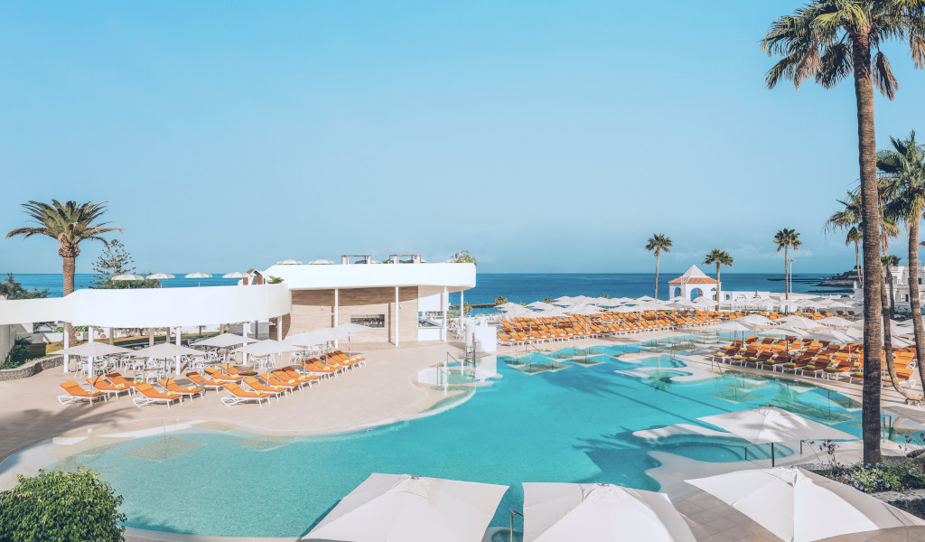 Piscine et chaises longues à Tenerife avec vue sur la mer.
