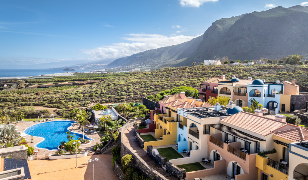 Complexe hôtelier coloré avec piscine et paysage montagneux à Tenerife.