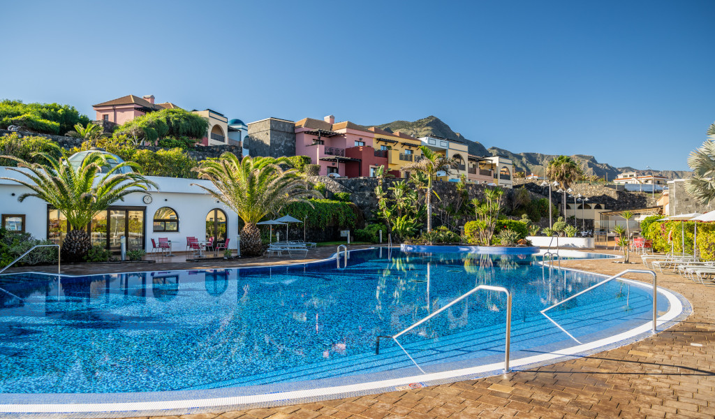 Piscine entourée de palmiers et bâtiments colorés à Adeje, Tenerife.