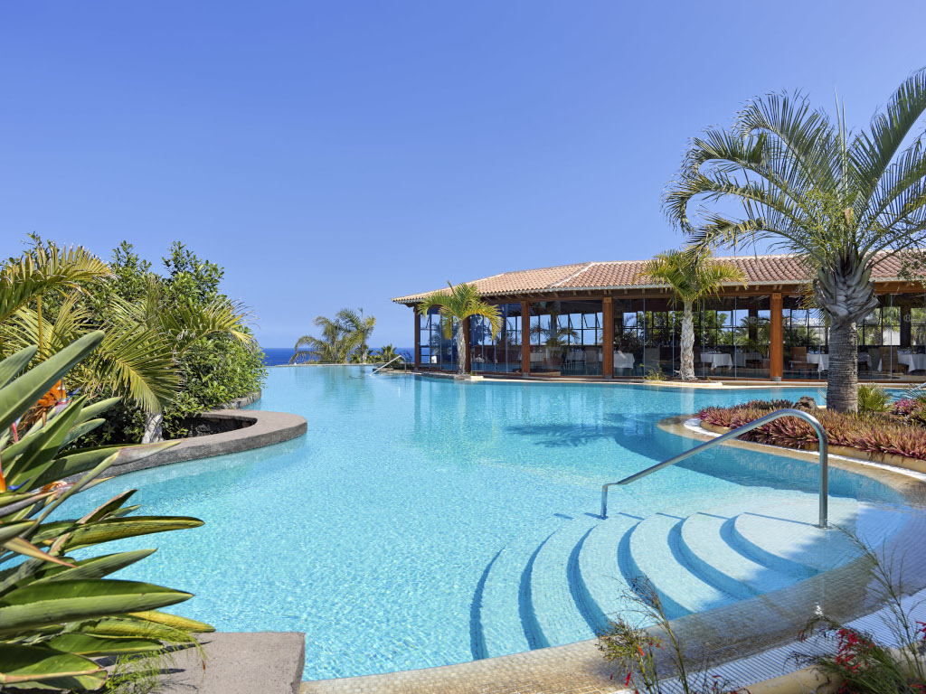 Piscine extérieure avec escaliers et palmiers à Tenerife, vue sur la mer.