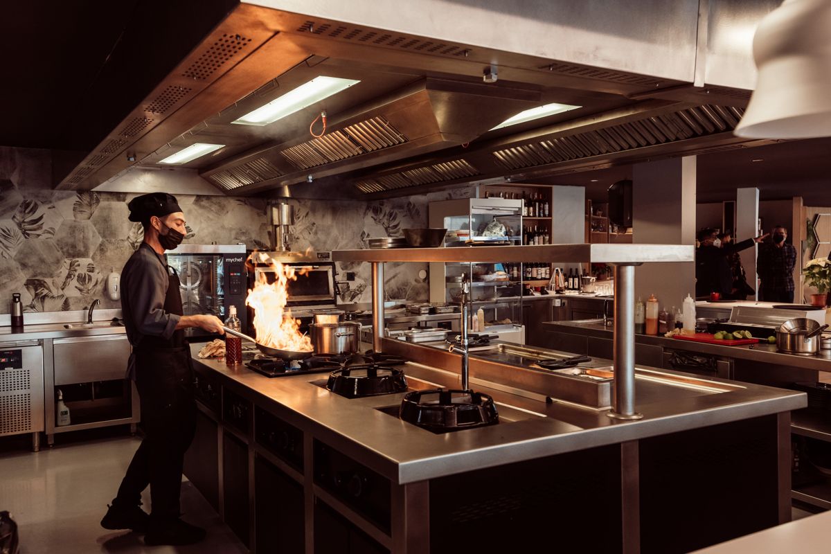 Chef cuisinant avec des flammes dans une cuisine professionnelle de Tenerife.