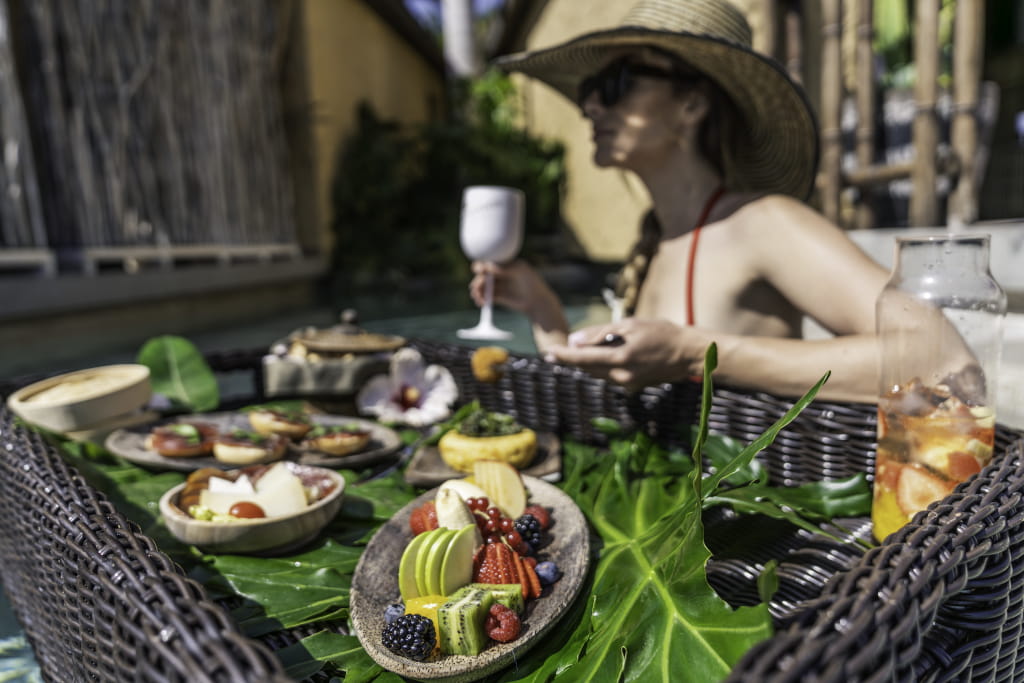 Une femme en maillot au bord de la piscine à Tenerife, un plateau de fruits devant elle.