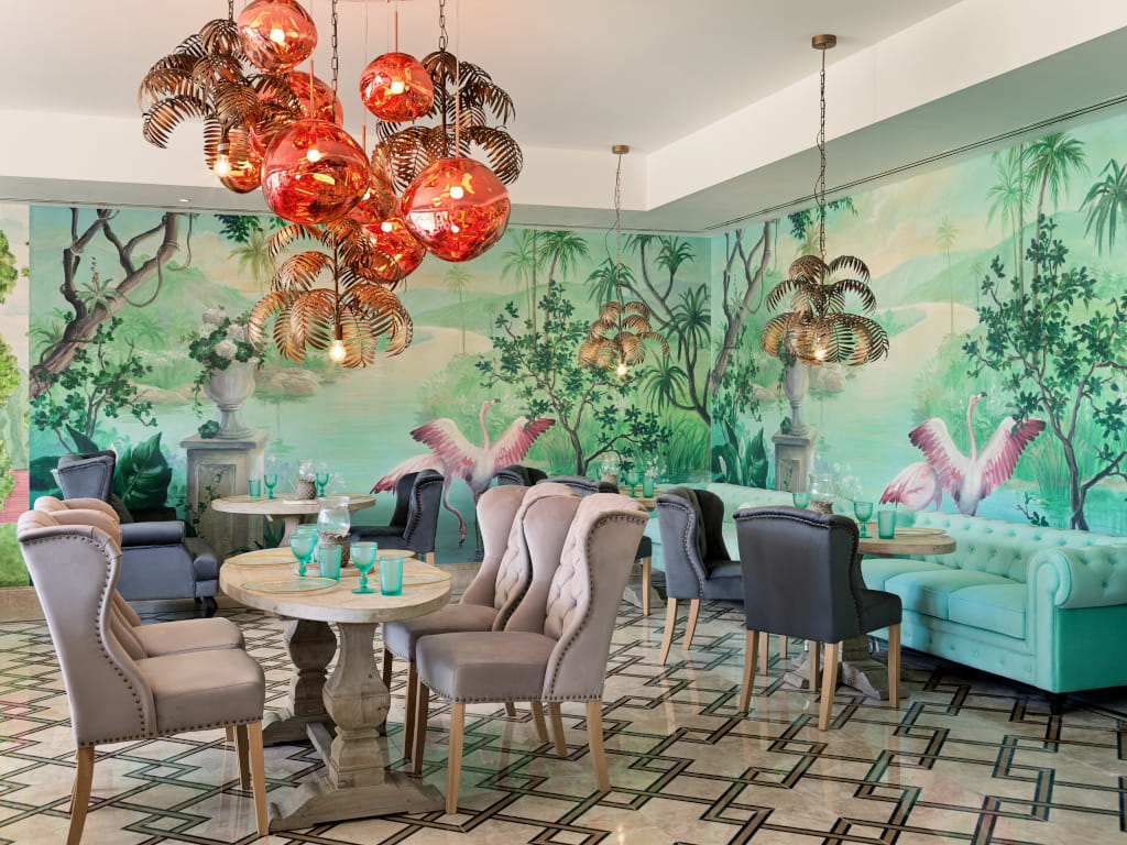 Intérieur d'un restaurant avec des tables, des chaises et un mur peint de flamants roses à Tenerife.