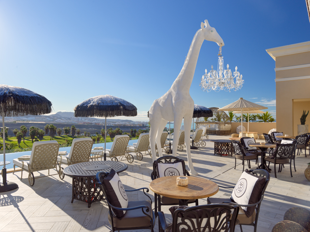 Terrasse avec chaise longue, parasols, girafe blanche et vue sur Costa Adeje à Tenerife.