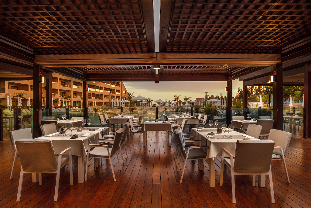 Restaurant élégant avec tables dressées, vue extérieure sur Tenerife au coucher du soleil.