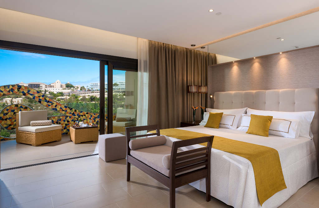 Chambre d'hôtel moderne avec vue sur Costa Adeje, Tenerife, et terrasse meublée.