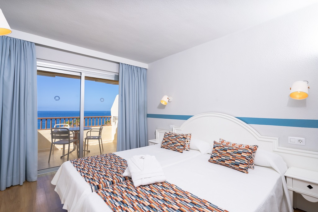 Chambre d'hôtel avec vue sur la mer à Tenerife, balcon avec table et chaises.