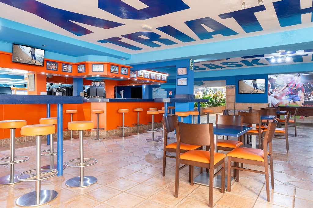 Bar sportif coloré avec des tabourets orange à Tenerife.