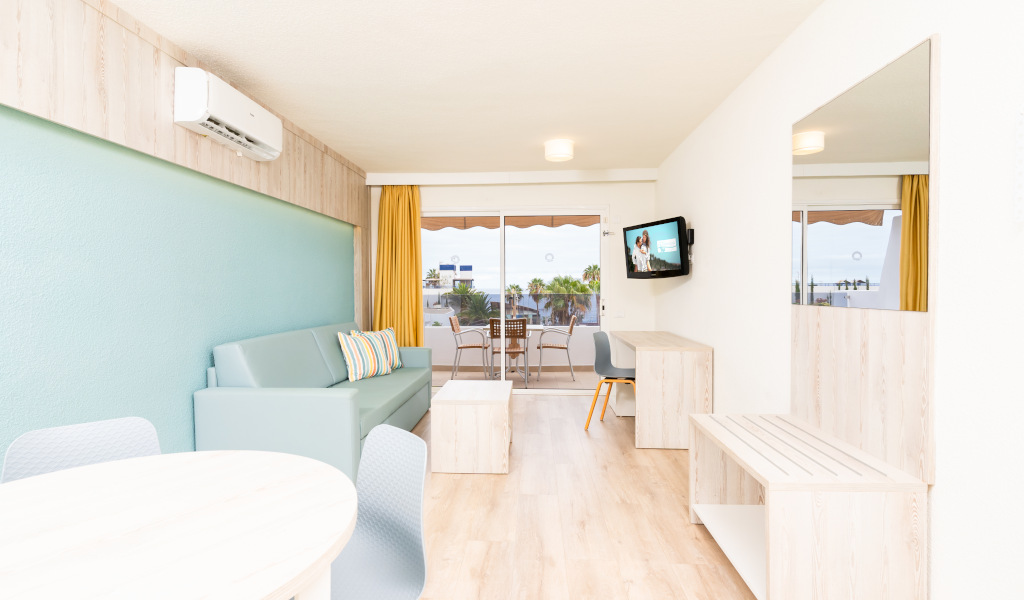 Salon moderne avec canapé, table à dîner et balcon à Tenerife.