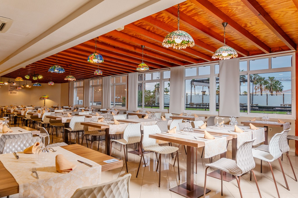 Salle de restaurant lumineux à Tenerife avec tables dressées et chaises blanches.